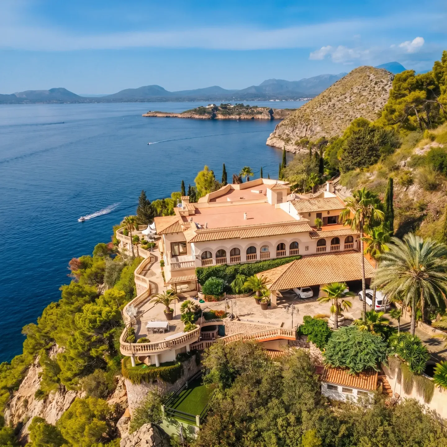 Aerial view of a luxury villa in Mallorca, surrounded by lush greenery and overlooking the sea.