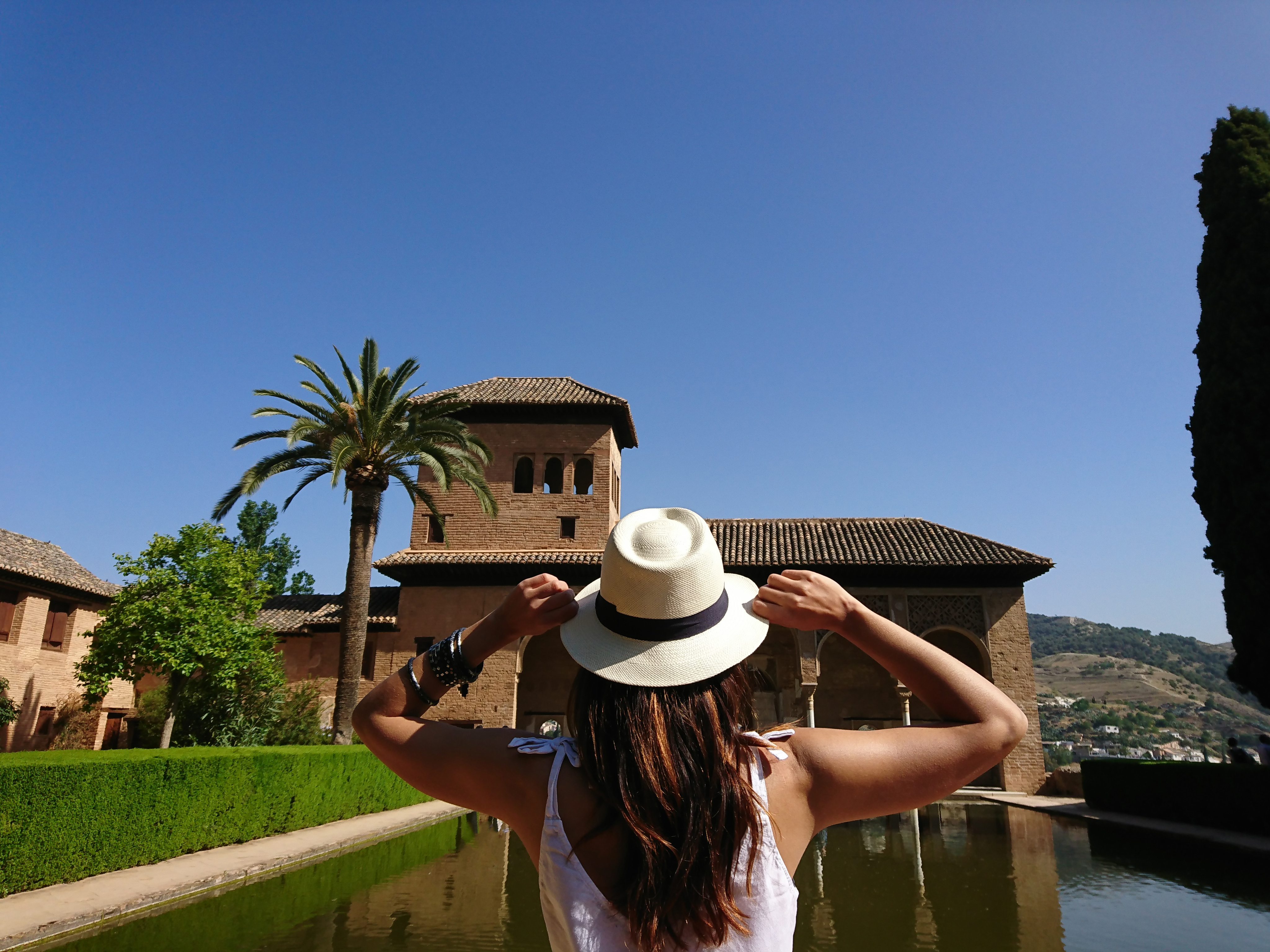 Woman in front of apartment building, wearing white hat